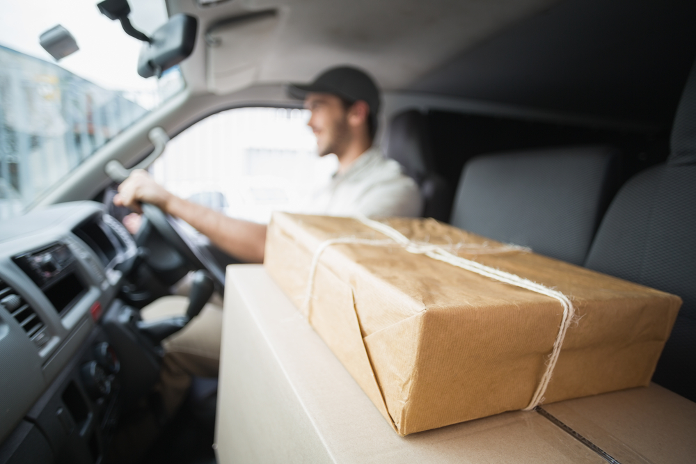 Delivery driver driving van with parcels on seat outside the warehouse Delivery driver driving van with parcels on seat outside the warehouse